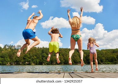 Happy Family With Two Kids In Summer On Vacation Jumps In A Lake