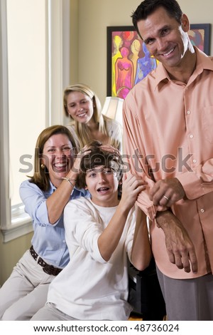 Happy family with two teenage children laughing together at home