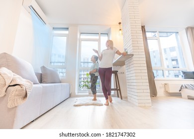 Happy Family Under Air Conditioner, Mom Holding Remote Control Switch On Conditioning In Living Room Adjust Comfort Temperature For Daughter, Climate System At Modern Home