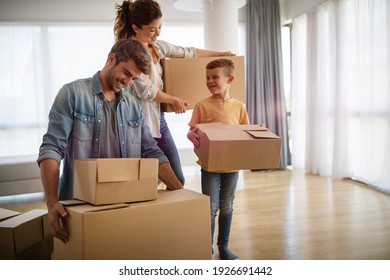 Happy Family Unpacking Boxes In New Home On Moving Day