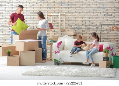 Happy family unpacking cardboard boxes in room at new house
