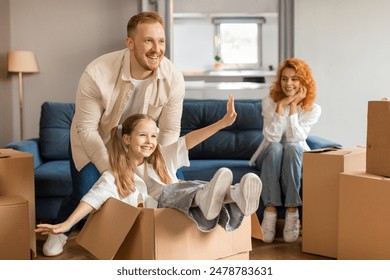 Happy family unpacking during move, father and daughter having fun, girl sitting in cardboard box - Powered by Shutterstock