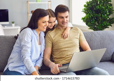 A happy family uses a laptop together while sitting at home. - Powered by Shutterstock