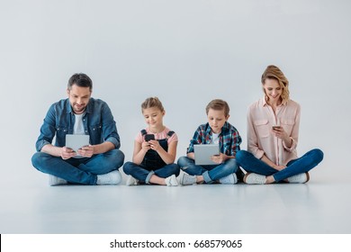 happy family using digital devices while sitting on the floor