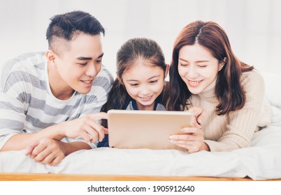 Happy Family Using Digital Tablet In Bed