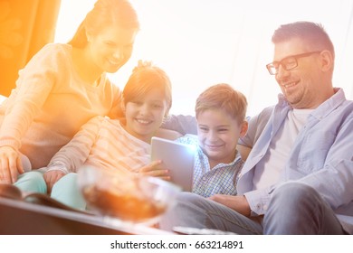 Happy Family Using Digital Tablet Together In Living Room