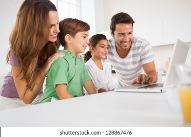 Happy Family Using A Laptop In Kitchen