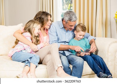 happy family using phone on sofa in the living room - Shutterstock ID 362209763