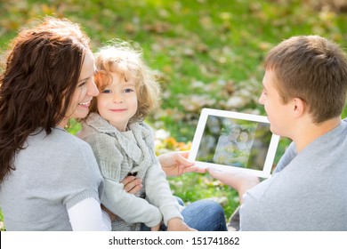 Happy Family Using Tablet PC Outdoors In Autumn Park