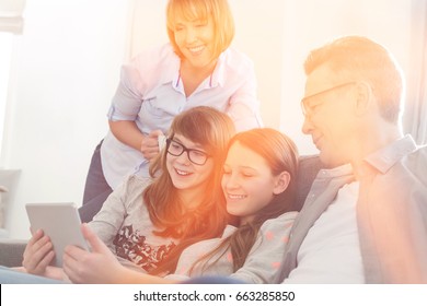 Happy Family Using Tablet PC On Sofa At Home