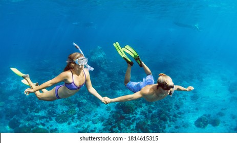 Happy family vacation. Young couple in snorkeling mask hold hand, free dive underwater with fishes in coral reef sea pool. Travel lifestyle, watersport adventure, swim activity on summer beach holiday - Powered by Shutterstock