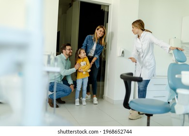 Happy Family At Visit In The Dentist Office. Female Dentist Greets The Patients Nicely And Shows The Girl Where To Sit.