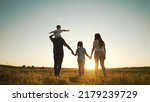 Happy family walk in field in nature.Parents and children are free and active people in nature.Healthy and cheerful family at picnic in the park.Summer walk in the park at sunset.Parents and children