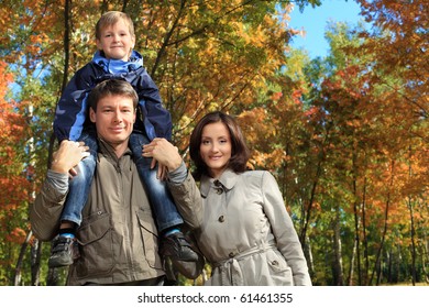 Happy Family Walking At The Autumn Park.