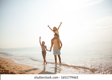 Happy family walking in the beach with fun. People travel togethe. The man holding the pteteen kid on shoolders and hand up