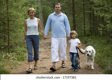 Happy Family Walking With Dog In The Forest