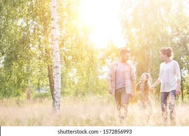 Happy Family Walking In Field With Lens Flare In Background