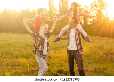 Happy Family Walking In Field And Looking At Sunset