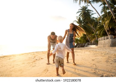 Happy Family Walking On The Beach At Sunset