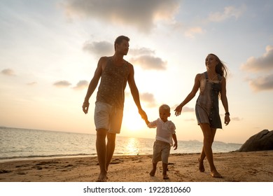 glückliche Familie, die bei Sonnenuntergang am Strand spaziert