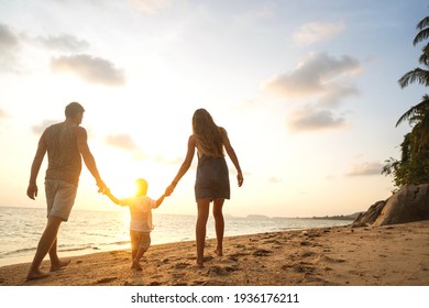 glückliche Familie, die bei Sonnenuntergang am Strand spaziert