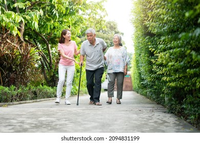 Happy family walking together in the garden. Old elderly using a walking stick to help walk balance. Concept of Love and care of the family And health insurance for family