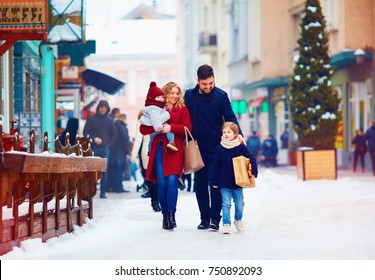 Happy Family Walking Together At Snowy City Street During Winter Holidays