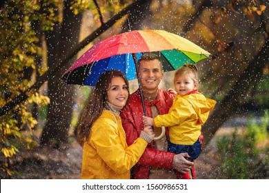 Happy Family Walking Under The Rain At Autumn Park