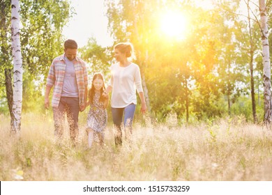 Happy Family Walking In Wheat Field With Yellow Lens Flare In Background