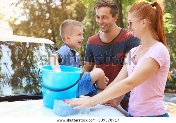Happy family washing car on\
street