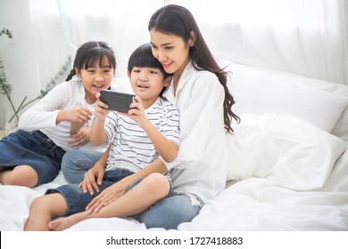 Happy family watch movie on smartphone. mother cuddle son and daughter video chat with friend or family for social distancing. stay home during Coronavirus or COVID19. new normal lifestyle insurance