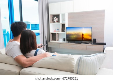 Happy family watches television while sitting on the sofa.