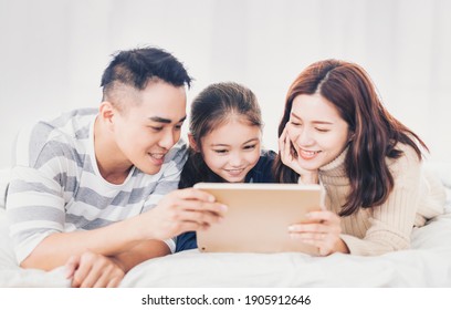 Happy Family Watching The  Digital Tablet In Bed