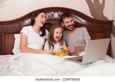 Happy Family Watching Movie In Bed And Eating Chips.