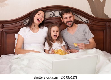 Happy Family Watching Movie In Bed And Eating Chips.