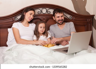 Happy Family Watching Movie In Bed And Eating Chips.