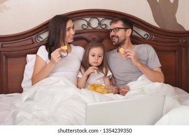 Happy Family Watching Movie In Bed And Eating Chips.