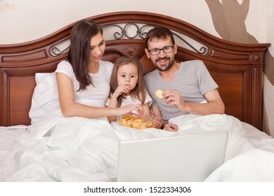 Happy Family Watching Movie In Bed And Eating Chips.