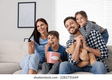 Happy family watching movie at home. Mother changing TV channels with remote control - Powered by Shutterstock