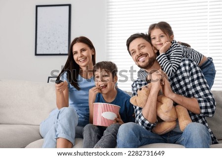 Happy family watching movie at home. Mother changing TV channels with remote control Foto stock © 