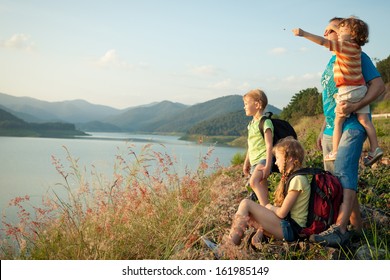 Happy Family Watching The Sunset On The Lake