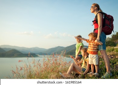 Happy Family Watching The Sunset On The Lake