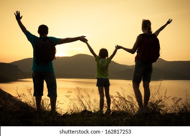 Happy Family Watching The Sunset On The Lake