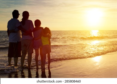 Happy Family Watching The Sunset On The Beach