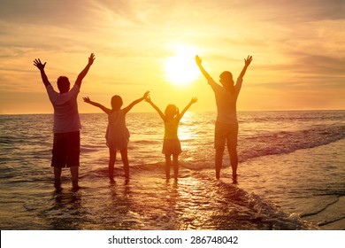 Happy Family Watching The Sunset On The Beach