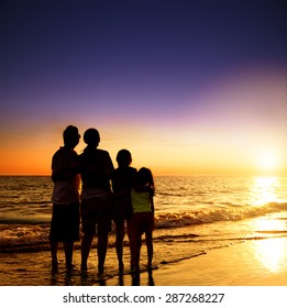 Happy Family Watching The Sunset On The Beach