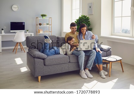 Happy family watching together video online in a laptop while sitting comfortably at home.