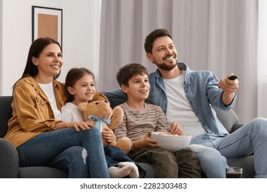 Happy family watching TV at home. Father changing channels with remote control - Powered by Shutterstock