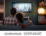 Happy family watching TV, movies in the evening at home. Couple spending time together.