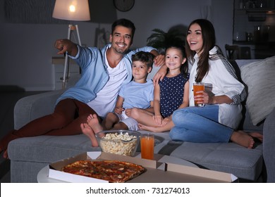 Happy family watching TV on sofa at night - Shutterstock ID 731274013